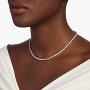 Round moissanite tennis necklace in white gold worn with a white off shoulder top
